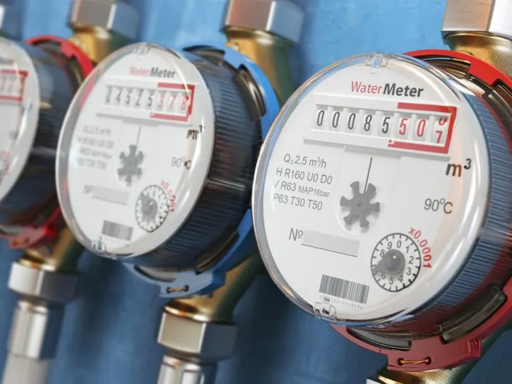 Row of water meters of cold and hot water on the wall background
