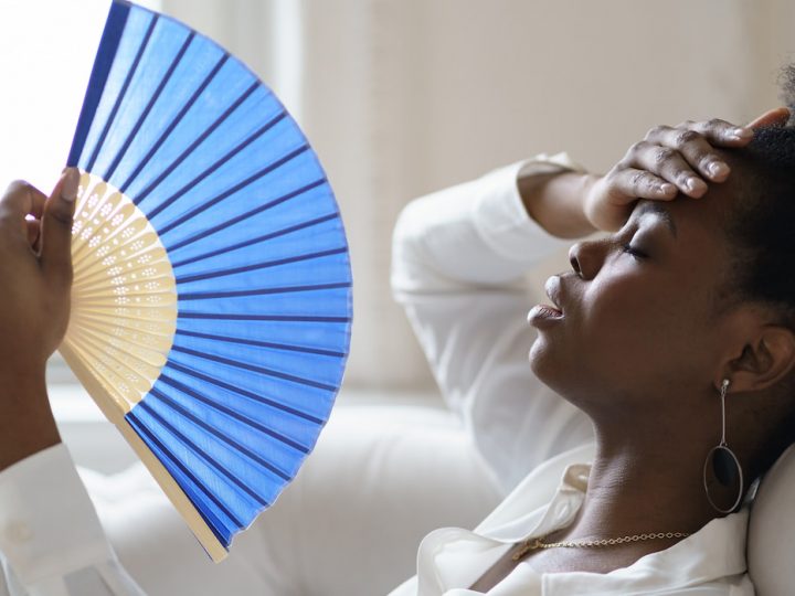 Woman on the sofa with wave fan suffer from heat sweating