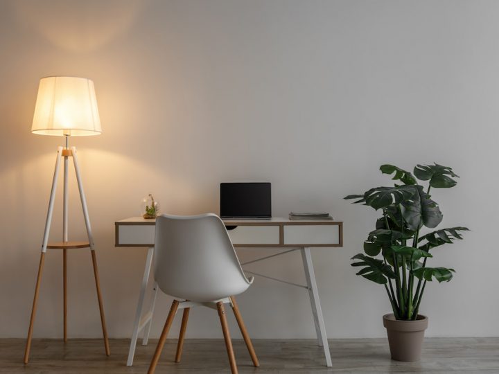 chair, laptop on table, glowing lamp and potted plant on floor