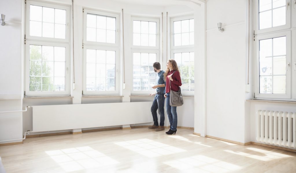 Couple looking around in empty apartment
