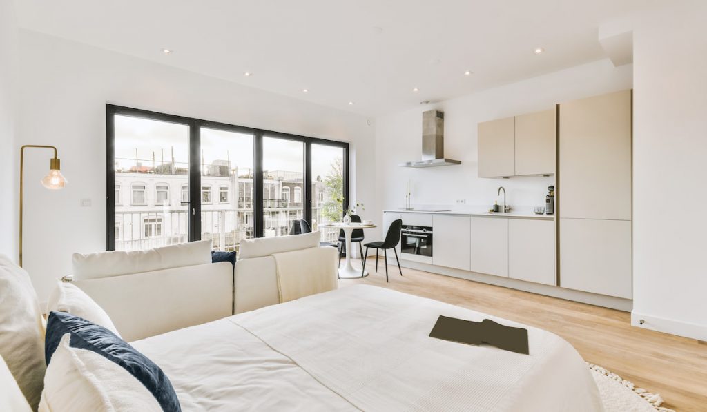 Modern minimalist studio apartment interior design with open white kitchen and dining area