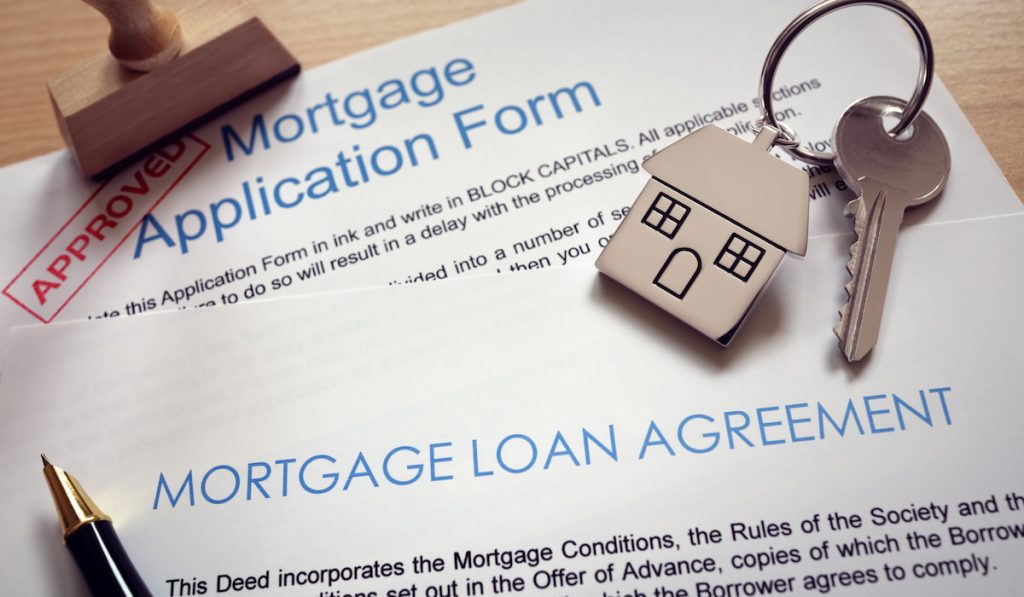 Mortgage loan agreement application with key on house shaped keyring

