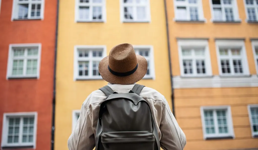 Rear view of man outdoor looking at colorful apartment building 