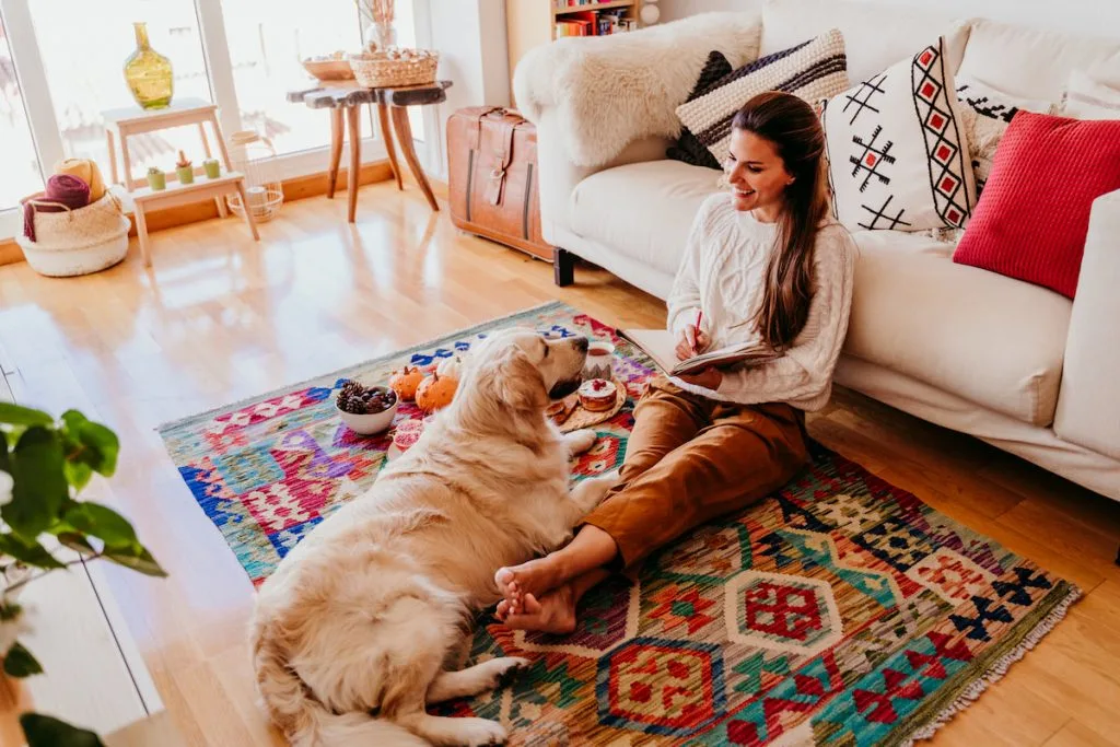 woman enjoying cup of coffee during breakfast at home.Writing on notebook.cute golden retriever dog