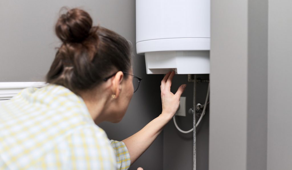 woman regulates the temperature on an electric water heater