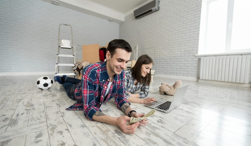 young couple lying on the floor in an empty apartment  and managing budget 