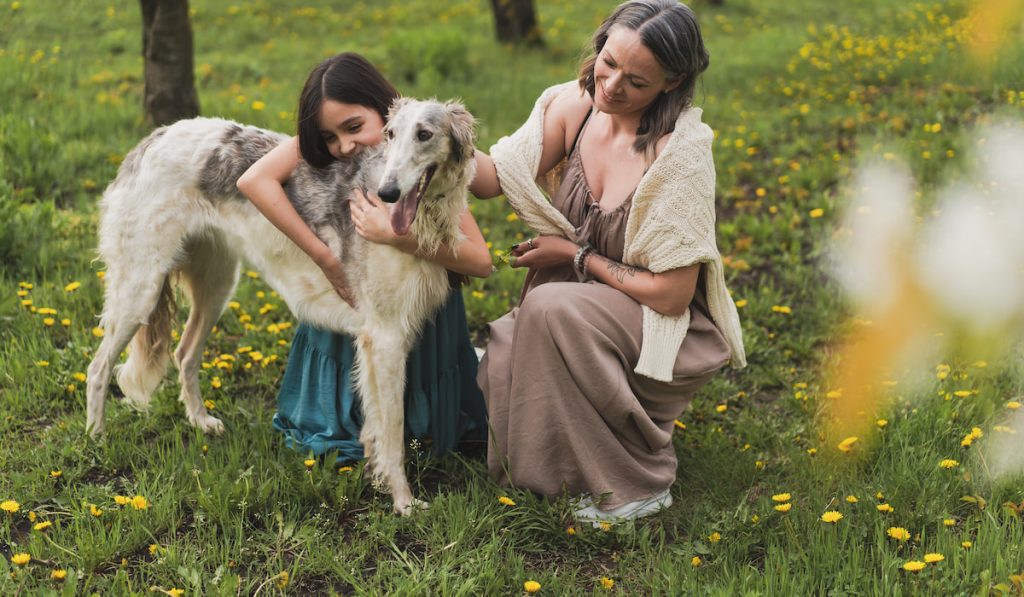 mom and daughter in the garden with their greyhound pet