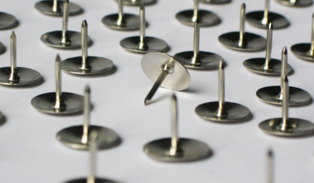 Metal stationery thumbtacks lie on a white background