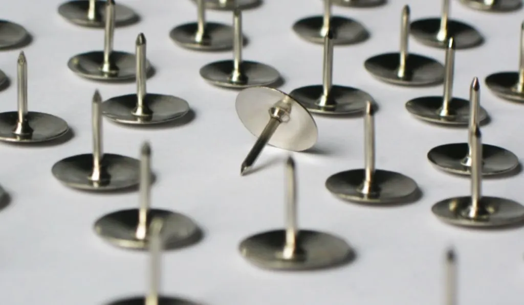 Metal stationery thumbtacks lie on a white background

