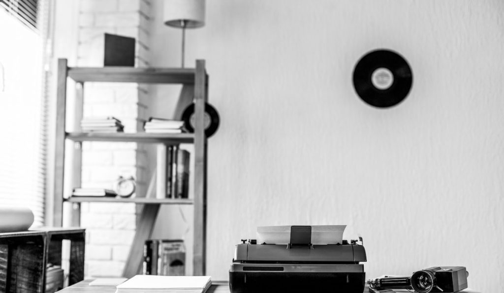 Vintage old typewriter at wooden desk table and vinyl record on a wall