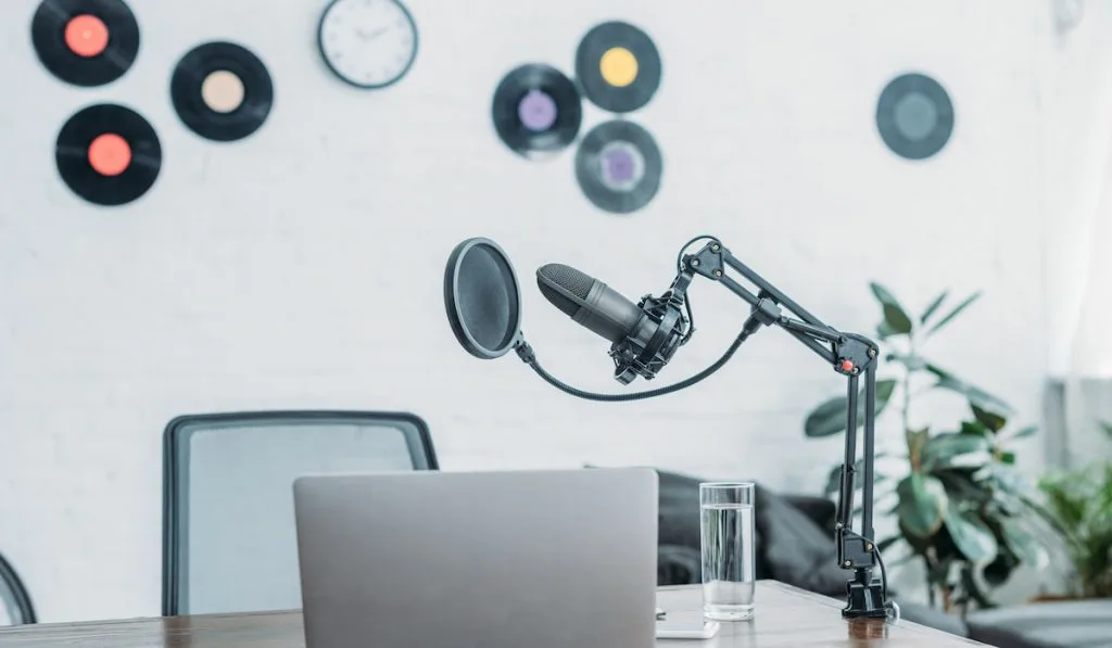 microphone, laptop,  and vinyl records design on a wall in broadcasting studio