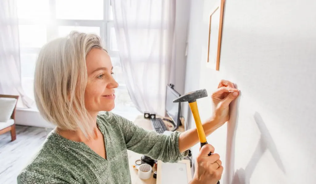 woman hammering nail to wall